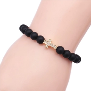 Macro view of matte black tiger eye beads with a gold zircon cross on a wrist