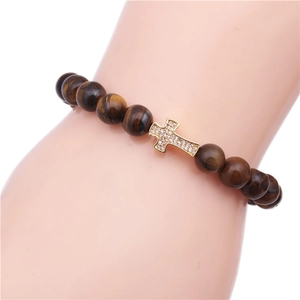 Macro shot of tiger eye beaded bracelet featuring a gold cross pendant with cubic zirconia