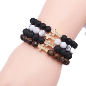 Detail of beaded bracelet set with volcanic stone, tiger eye, and zircon cross charms