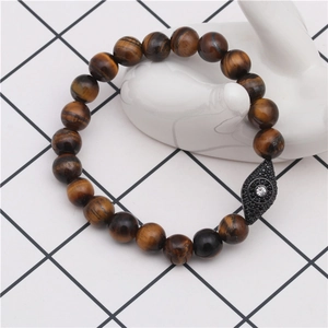 Macro shot of tiger eye stone bracelet featuring a pave-set evil eye charm on a hand mold