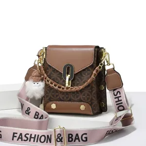 Detail of brown vintage square bag with metal lock and fashion embroidered strap