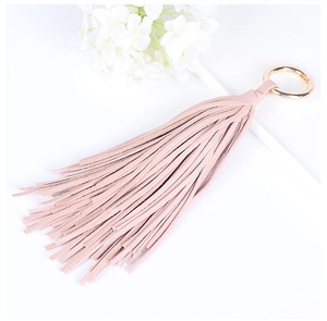 Porte-clés à pampilles en cuir rose avec anneau doré sur fond de fleurs blanches