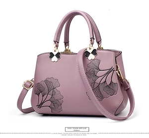 Detail of purple PU leather handbag with elegant black ginkgo leaf embroidery and gold charms