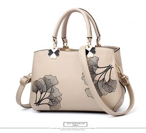 Detail of khaki faux leather shoulder bag with black leaf embroidery and clover charm