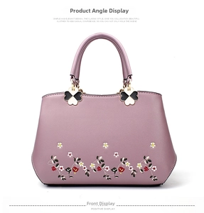 Close-up of elegant floral embroidery and clover metal hardware on purple tote bag
