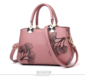 Detail view of pink PU leather tote bag with leaf embroidery and clover charms