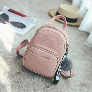 Detail of pink faux leather mini backpack with grey pompom and ribbon tag