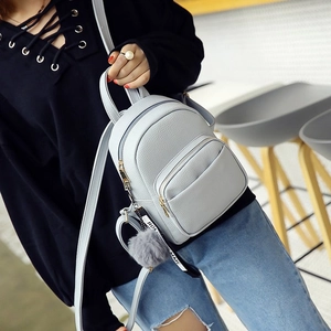Detail of light gray pebble leather backpack with decorative fur ball and HOME charm