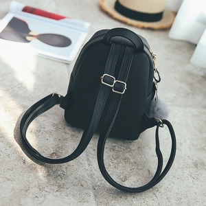 Detail view of mini black leather backpack with adjustable straps and grey pompom charm