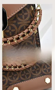 Detail of woven handle with gold chain on a brown monogram square crossbody bag