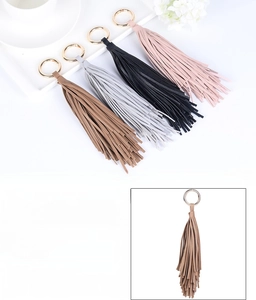 Détail de porte-clés à pompon en cuir avec anneaux dorés déclinés en quatre couleurs
