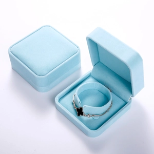 Detailed top view of a light blue velvet jewelry gift box with a clover charm bracelet