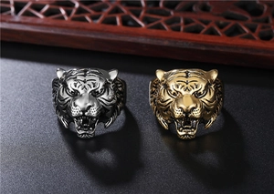 Detail view of two tiger head rings in gold and silver finish on a textured display base