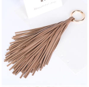 Détail d'un porte-clés à franges en cuir marron avec un anneau métallique doré pour sacs
