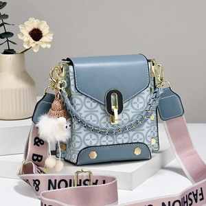 Blue geometric crossbody bag with gold chain handle and wide fashion strap on white decor