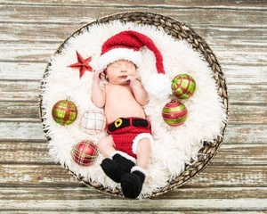 Detail of handmade crochet newborn Christmas outfit with red hat and boots on white fur