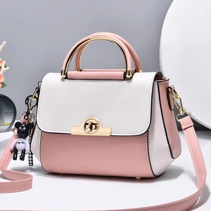 Sac bandoulière rose et crème avec fermoir tournant doré et petit pendentif ours
