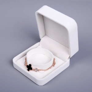 Detail of rose gold clover bracelet with black enamel and stones on a velvet jewelry box