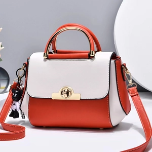 Sac bandoulière orange et beige avec poignée dorée et accessoire ours de style moderne