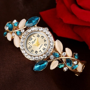 Detailed macro view of the gold-toned vine-style bracelet watch with blue leaf-shaped stones