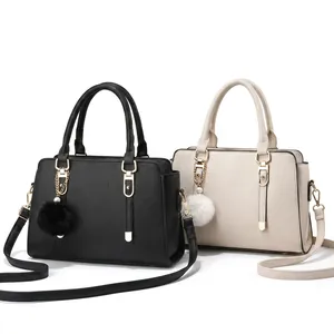 Detail of lychee pattern leather tote bag with metallic logo and plush fur ball charm