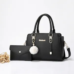 Close-up of black lychee grain leather handbag set with gold logo and plush pompom