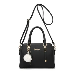 Detail of black lychee grain cowhide handbag with gold hardware and white pompom charm