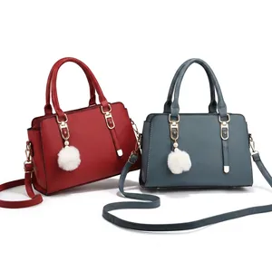 Detail of red and blue litchi pattern leather handbags with golden hardware and fuzzy charms