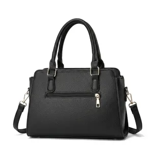 Detail of black lychee grain leather handbag with gold hardware and plush charm