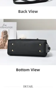 Detail view of black lychee leather bag bottom with gold metal studs and white fur ball