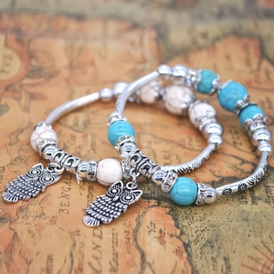 Macro shot of bohemian beaded bracelets with antique silver owl charms on vintage map