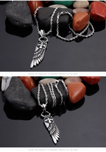 Detail of silver angel wings cross pendant in punk style on black reflective stones