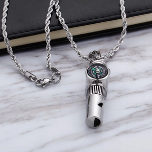 Compass and whistle pendant on stainless steel twist chain over marble surface