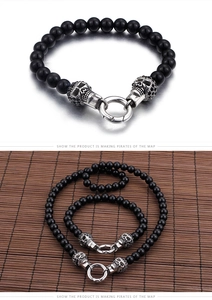 Macro detail of black beads and silver skull charms on punk stainless steel jewelry set
