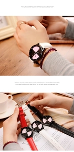 Close-up of three quartz watches with red, white, and black leather straps on a wooden table