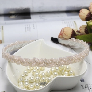 Braided pink pearl bead headband with elegant twisted design on a soft aesthetic background