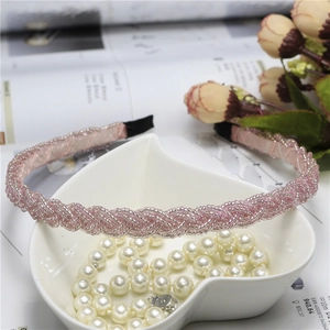 Elegant pink beaded braided headband placed on a white heart-shaped tray with pearls