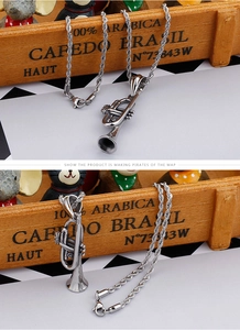 Macro shot of silver trumpet musical instrument pendant with twisted rope chain detail