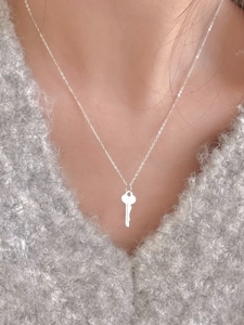 Close-up of S925 sterling silver key pendant necklace on a grey sweater