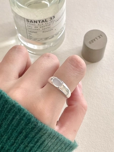 Detail view of a 925 sterling silver ring with oval white crystal on a finger