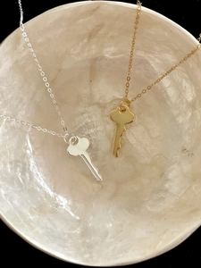 Detailed view of silver and gold key pendants on a mother-of-pearl tray background