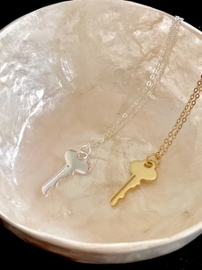 Close-up of gold and silver key pendants in a pearlescent bowl on black background