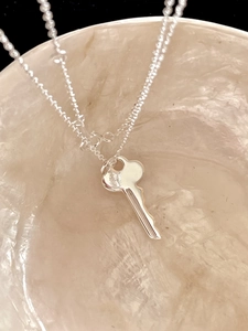 Macro detail of polished S925 sterling silver key pendant with elegant fine O-chain