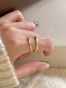 Close-up of a wavy hammered gold ring worn over a cozy cream-colored knit sweater sleeve