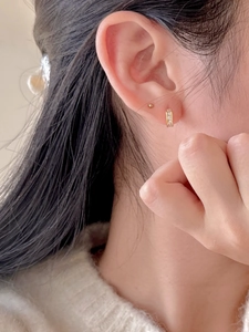 Close-up of 18K gold plated silver earrings with pavé zircon stones on model's ear