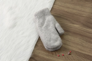 Dettaglio di muffole di peluche grigio chiaro su legno con ecopelliccia bianca e fiori