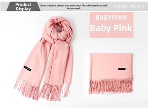 Detailed macro view of soft baby pink cashmere scarf texture with fringe and woven label