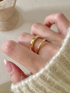 Detail of gold minimalist textured ring set worn with a soft knit sweater