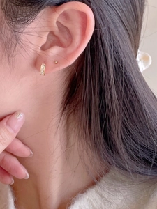 Close-up of gold huggie earring with three sparkling cubic zirconia stones on model