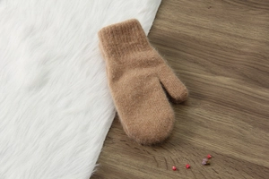 Dettaglio guanti in maglia di lana cammello con morbida texture peluche su sfondo caldo